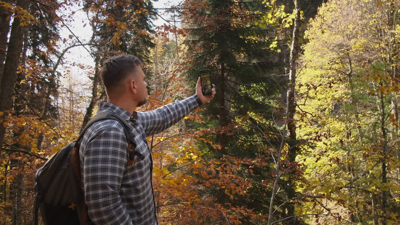 человек, делающий селфи в осеннем лесу.