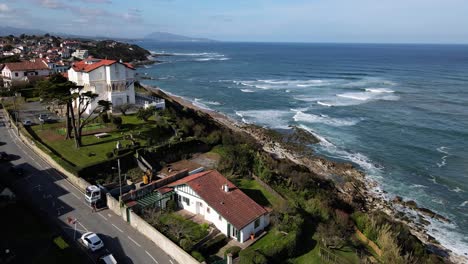 Un-Dron-Vuela-Sobre-La-Ciudad-Del-País-Vasco-Francés-Bidart-Con-Muchas-Casas-Vascas-A-Lo-Largo-De-La-Costa-Y-Parlamentia-Surf-Break-Con-Olas-Rompiendo-En-La-Orilla