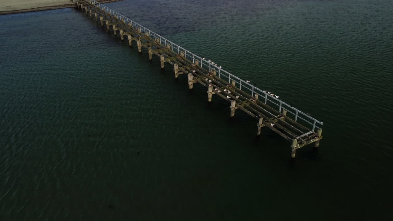vuelo de escalada sobre un puente descuidado y una playa con inclinación de la cámara