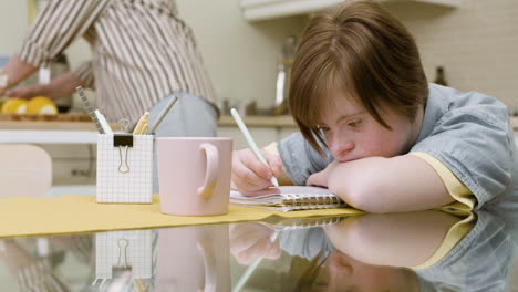 Teenager-doing-homework-in-the-kitchen-and-her-mother-has-made-juice