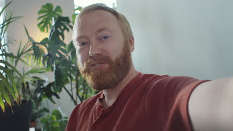 cheerful man talking on camera via web call at home