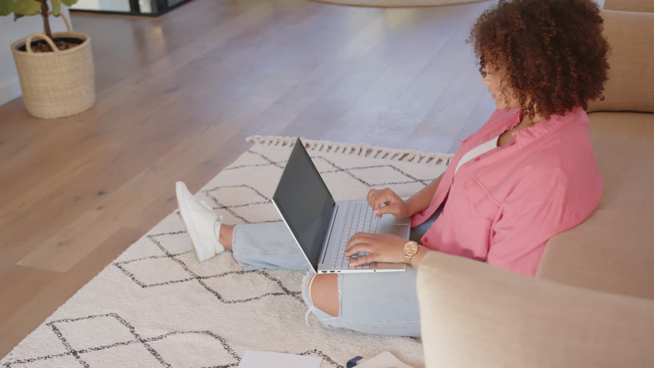 Sitting on floor, woman using laptop and working from home in living room