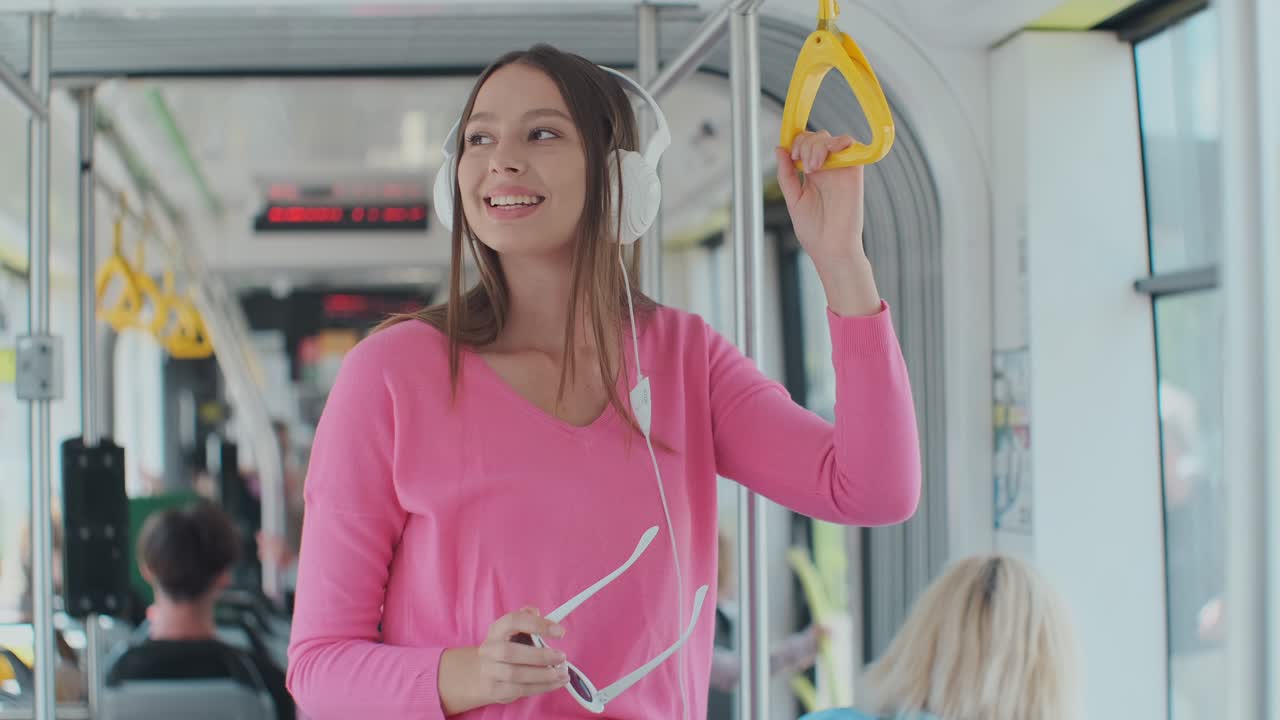 mujer joven sosteniendo la manija mientras se mueve en el tranvía moderno. pasajero feliz disfrutando del viaje en el transporte público.