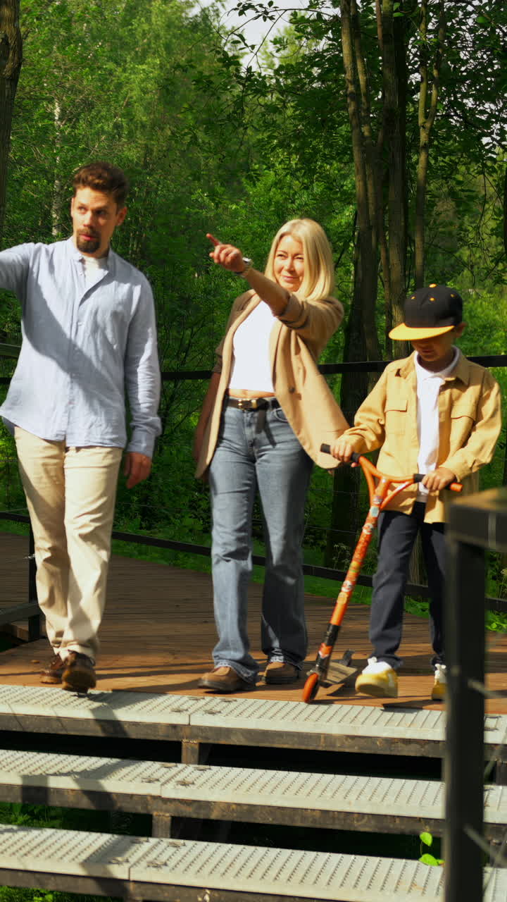 Ung familie med et barn går sammen på en tresti gjennom en vakker grønn skog.