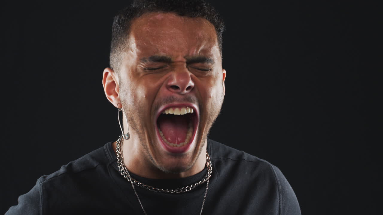 cabeza y hombros toma de estudio de un hombre enojado gritando a la cámara en cámara lenta