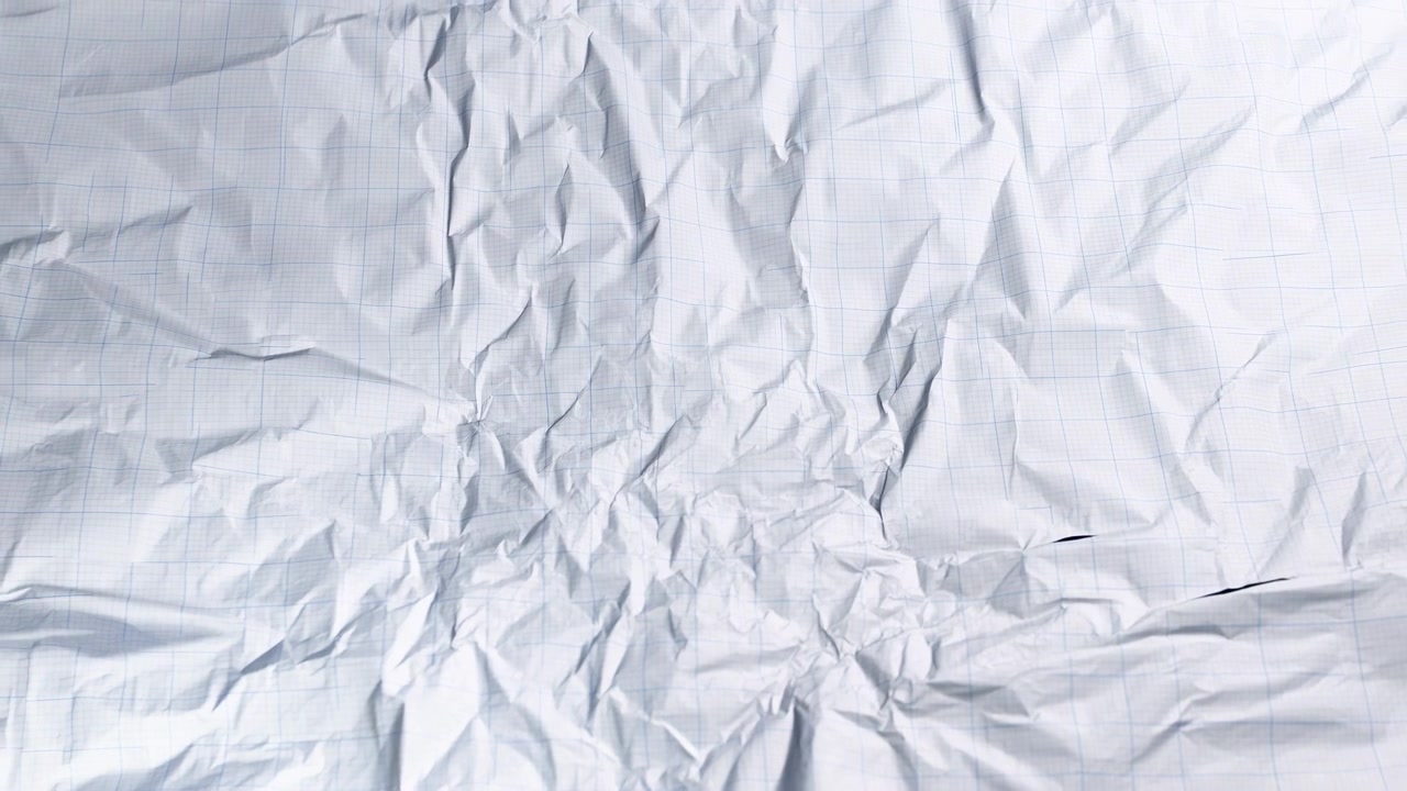 Topdown full-frame view of white graph paper crushed into tight center compression, showing radial creases, layered ridges, subtle troughs, tiny tears, and pale blue grid lines bent across rough