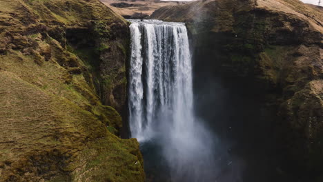 aerial pull back away from the skogafoss waterfall, sunny autumn day in iceland