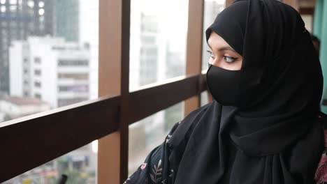 muslim woman in hijab looking out a window