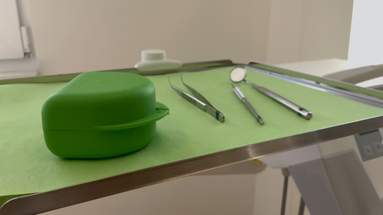 instrumentos dentales y una caja verde para aparatos ortopédicos se encuentran en una bandeja con una cubierta verde