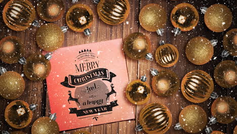 falling snow and merry christmas text note and bauble decorations on wood