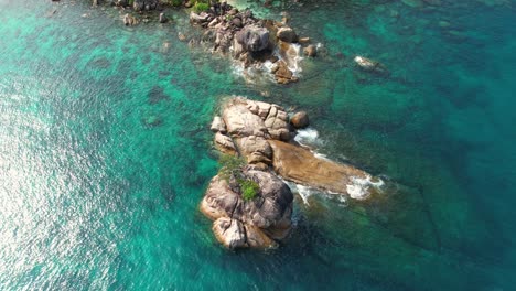 Zeitlupen-Drohnenaufnahme-Aus-Der-Vogelperspektive-über-Granitfelsen-Im-Meer-Auf-Der-Insel-Mahé,-Wellen-Und-Türkisfarbenes-Wasser,-Seychellen-1