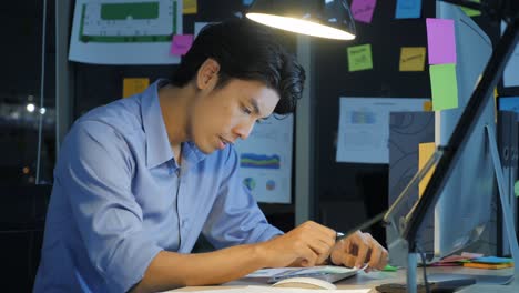 overworked businessman working late at night in the office, his desk is covered with paperwork, work overtime and deadlines concept