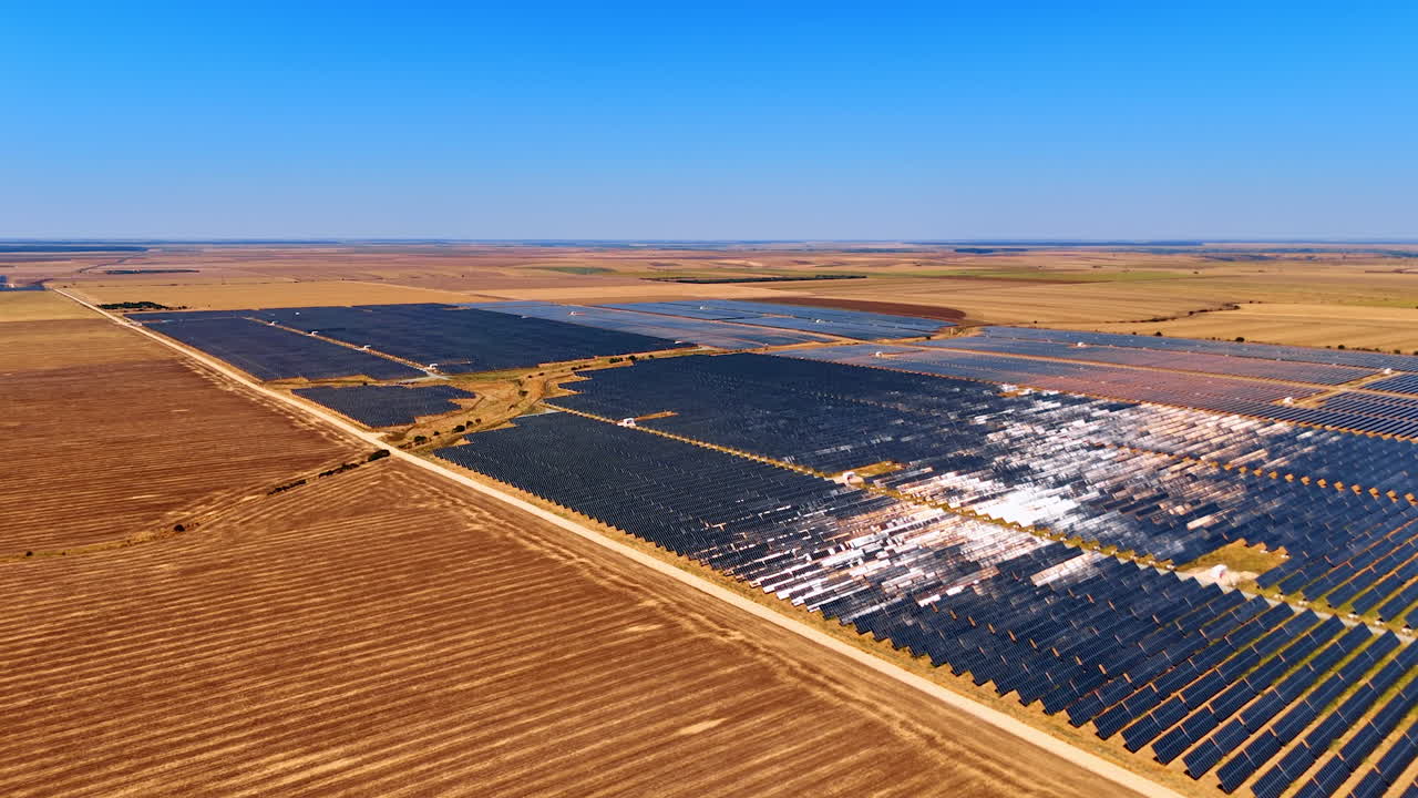 Solar farm fields under clear blue sky. Expansive solar farm stretches across flat land, capturing sunlight for energy production in a rural setting