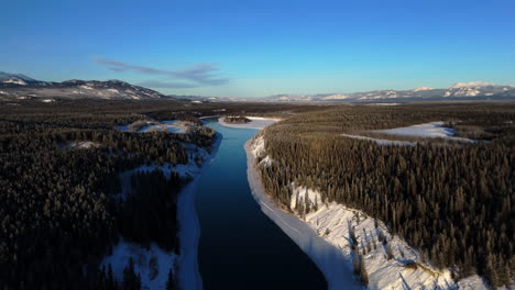 yukon river flowing through the forest during winter in canada - aerial drone shot