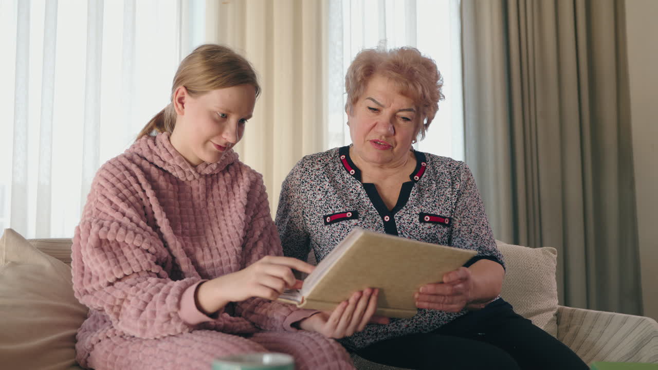 손녀 와 할머니 가 사진 앨범 을 살펴보고 있다