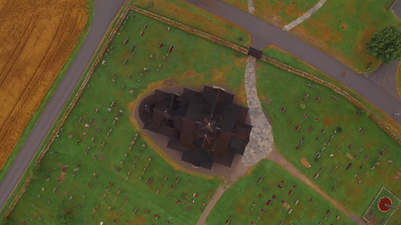 A black church surrounded by a cemetery and green landscape in norway, aerial view