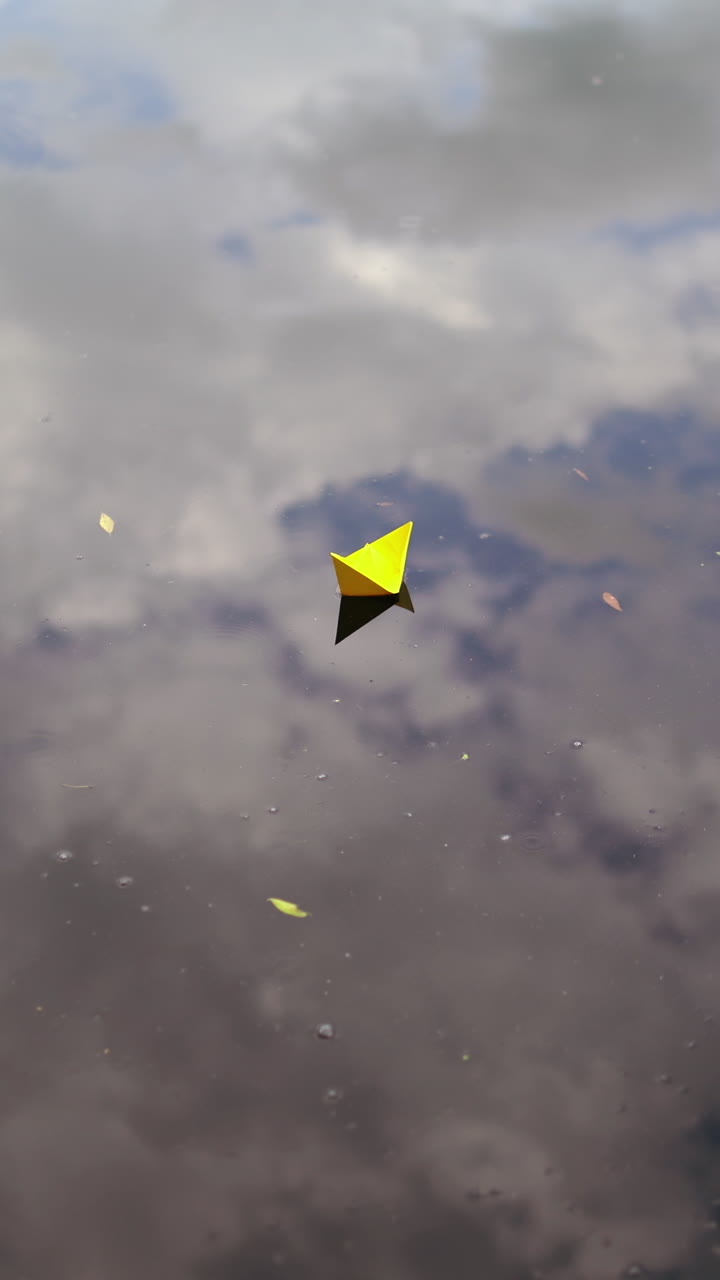 A paper boat sails along the river. Vertical video
