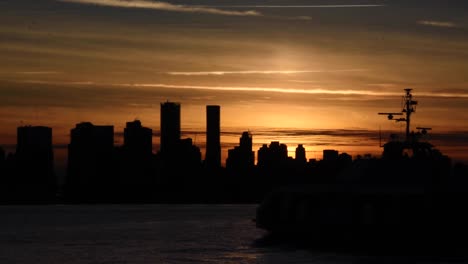 sunset behind the skyline sillhouettes of vancouver giving the sky a nice orange glow while a passenger ferry is sailing with it navigation lights in the vancouver harbour