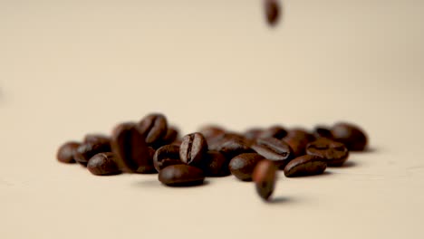 roasted coffee beans fall from above on a beige surface slow motion vintage look