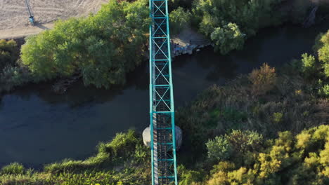 viejo puente de tren turquesa sobre un río en el campo de madrid, órbita aérea