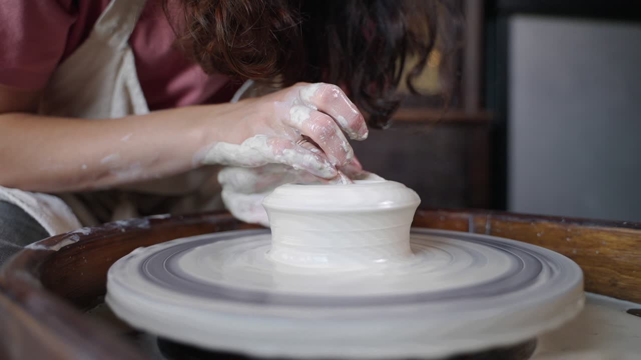 젊은 여성은 도자기 바에 세라 꽃병을 만들고, 점토 조각을 형성하고 있습니다.