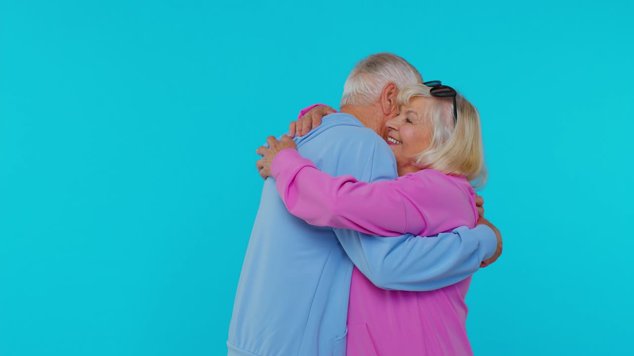 Coppia anziana romantica di nonni che si abbracciano, guardano la fotocamera e sorridono.