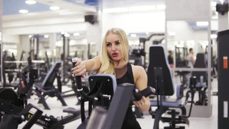 Young-female-bodybuilder-in-black-sportswear-doing-exersices-at-the-gym.-Building-up-strong-core-and-arms-muscles