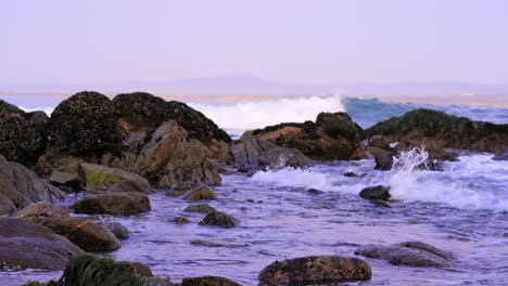 Slow-motion-waves-washing-over-tide-pool-rocky-coastline-morning-sunrise-seascape