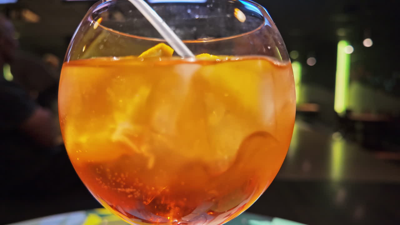Un vivace cocktail arancione con una cannuccia in una pista da bowling illuminata al neon