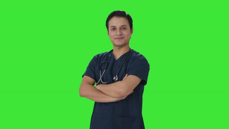 retrato de un feliz médico indio de pie con las manos cruzadas pantalla verde
