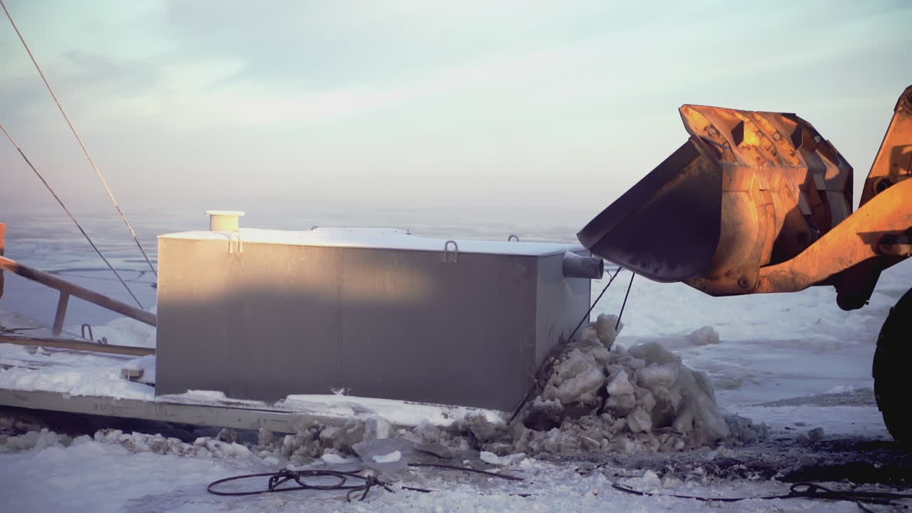 Escavatore che carica/scarica un serbatoio in condizioni invernali