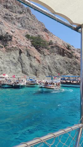 a group of boats are docked in the water near a rocky shore