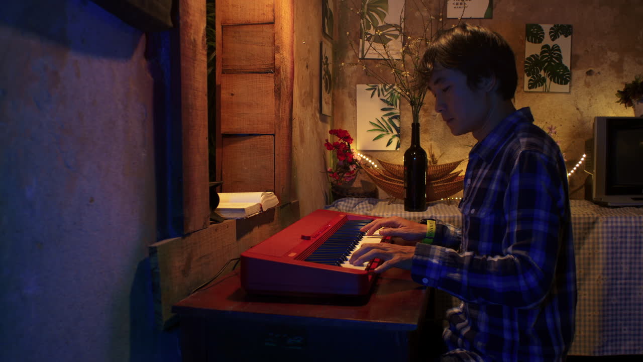 retrato lateral de un hombre asiático tocando el teclado del piano en casa por la noche