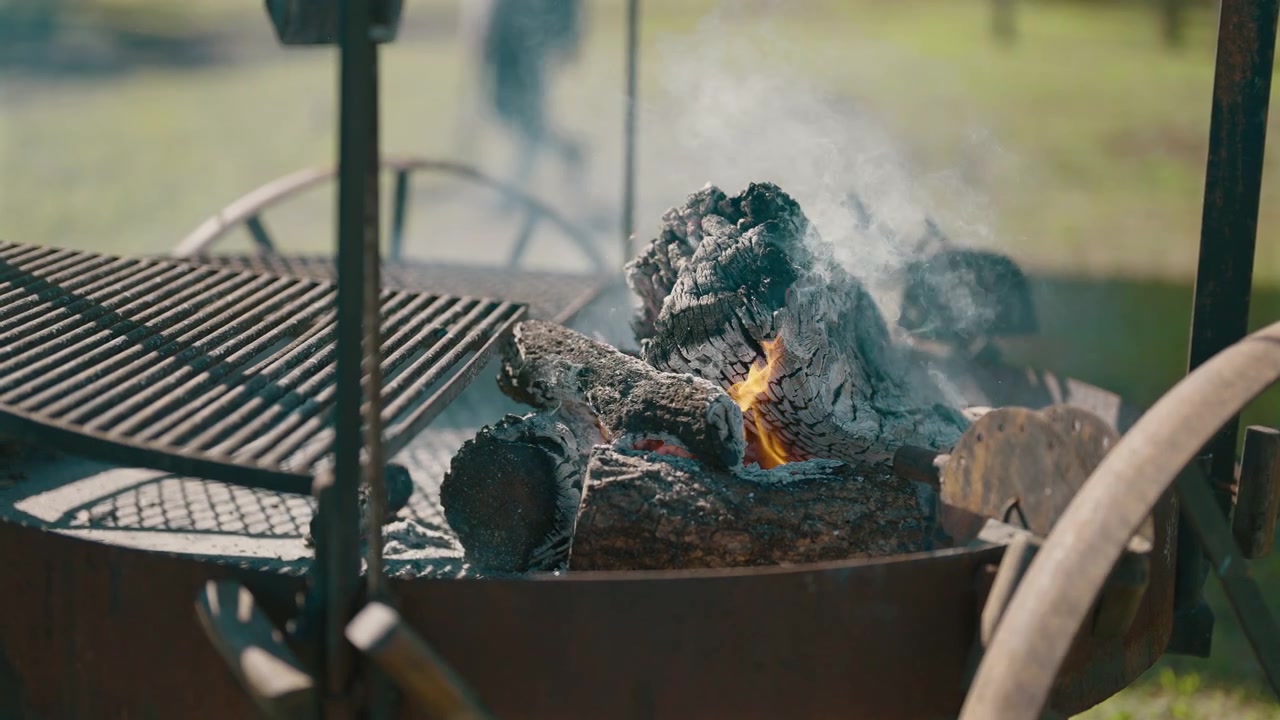 Brace di legna in preparazione per un asado argentino in un ambiente da campeggio all'aperto