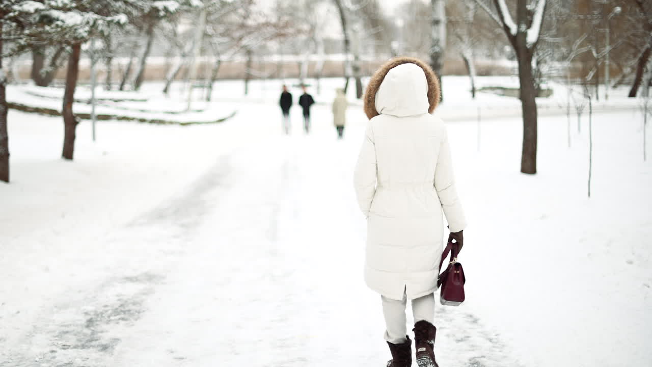Woman walking outside in a park with snow and pine trees