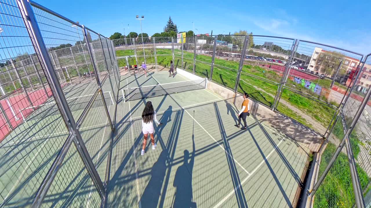 Amici che giocano a padel su un campo all'aperto in una giornata di sole.