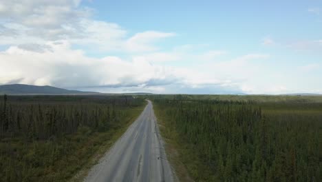 drone shot, truck driving on a country road, spruce forest in the background along the alaskan highway