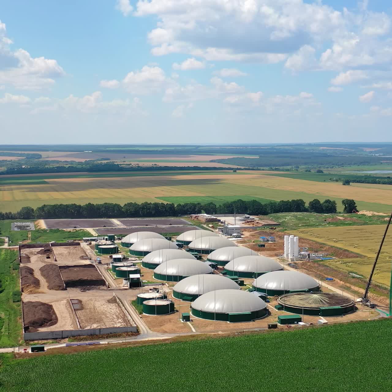 Renewable energy from biomass. Aerial view of big biogas plant between green agricultural fields