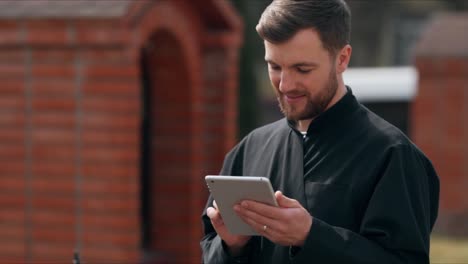 cute male monk in a black robe on the street with a laptop