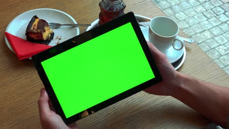 un hombre sostiene una tableta con una pantalla verde sobre una mesa con comida - primer plano desde arriba en el teléfono inteligente