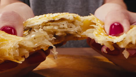 woman holding and eating a savory pastry filled with onions