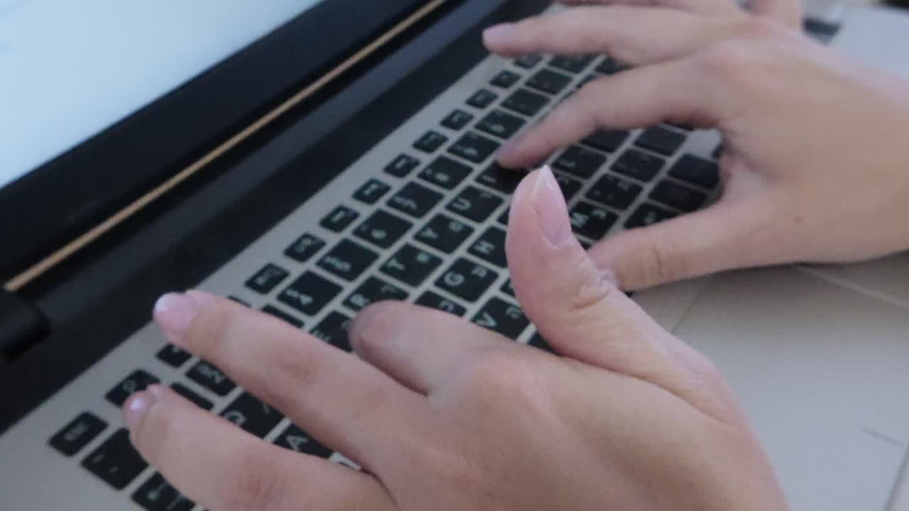 Front view of student's hands typing on a laptop keyboard. E-learning, research, or academic