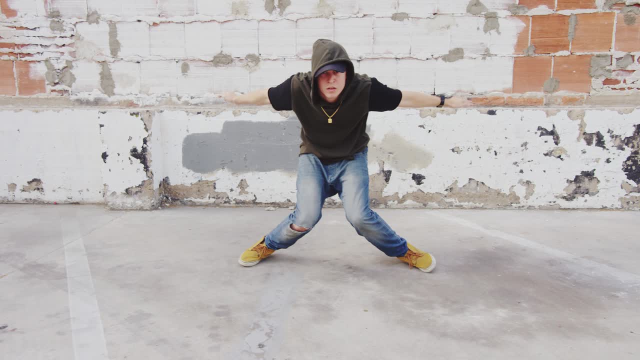 hombre de hip hop bailando afuera en la ciudad frente a una pared de ladrillo