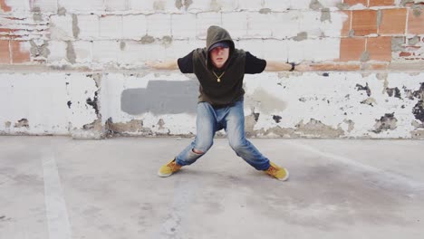 man hip hop dancing outside in city in front of brick wall