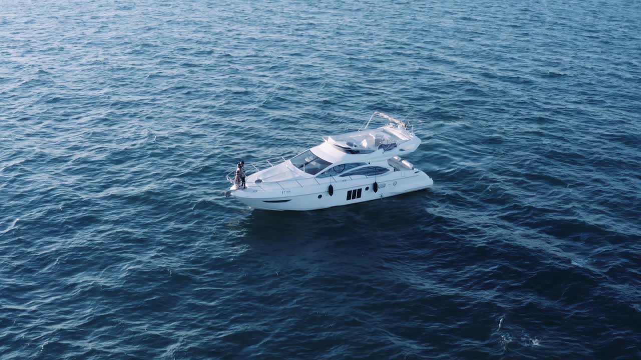 Coppia romantica in crociera di luna di miele - In piedi a prua di uno yacht alla deriva nel mare blu - orbita lenta, aerea