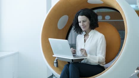 mujer de negocios sonriente escribiendo en una computadora portátil