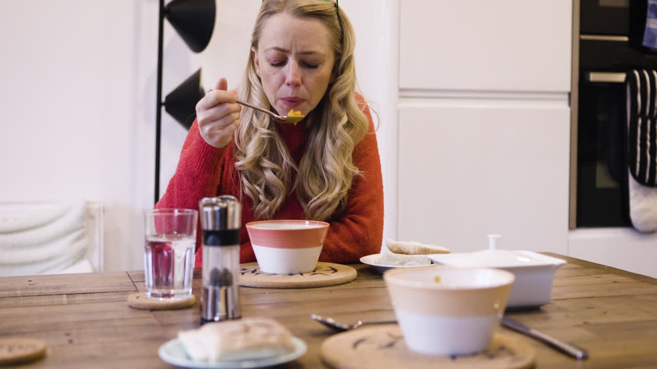 Woman eating soup at the kitchen table