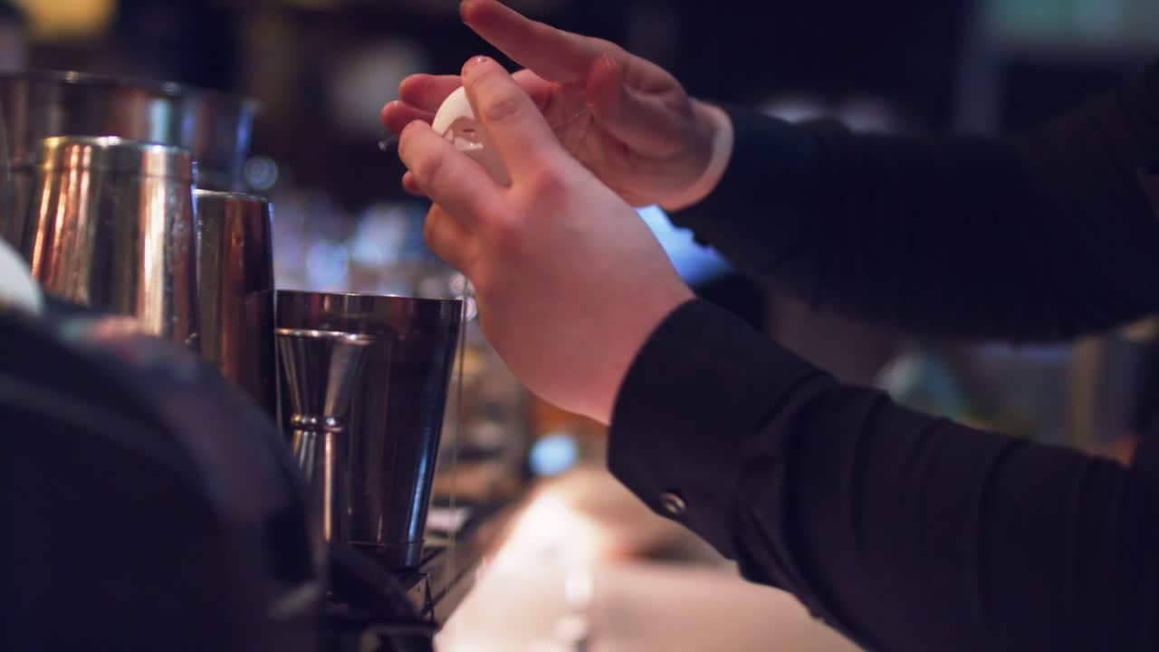 Bartender is breaking the egg for the cocktail