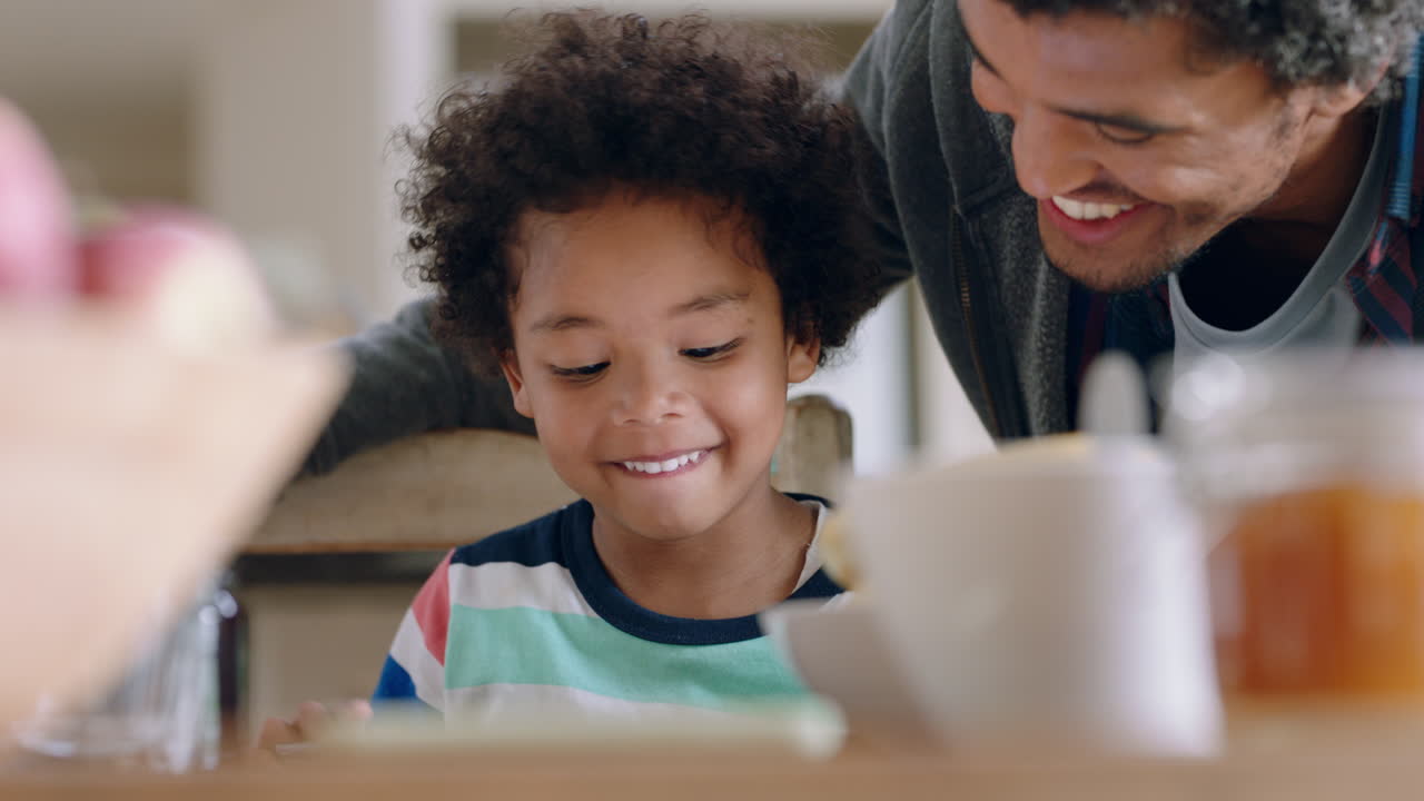 ragazzino che usa un tablet digitale che gioca a giochi che si diverte a imparare da suo padre che insegna a suo figlio la tecnologia touchscreen a casa