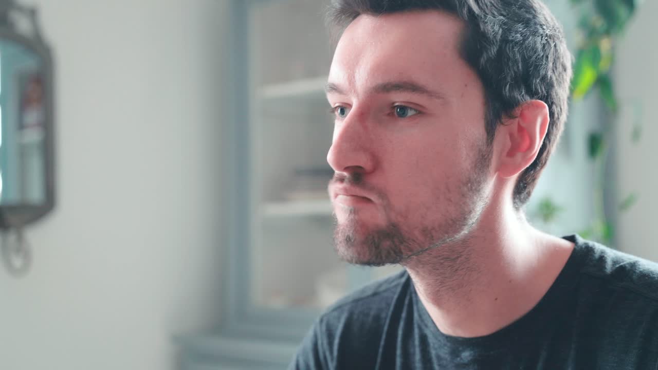 un joven caucásico muerde una hamburguesa en casa, una hamburguesa con queso disfruta comiendo, un retrato de cerca comiendo comida rápida, un concepto de alimentación poco saludable obesidad